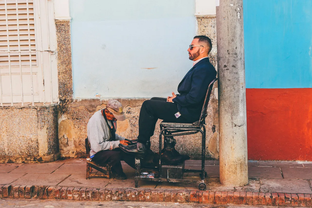 Man getting his shoes cleaned by a street shoeshiner. Photo by Nick Karvounis